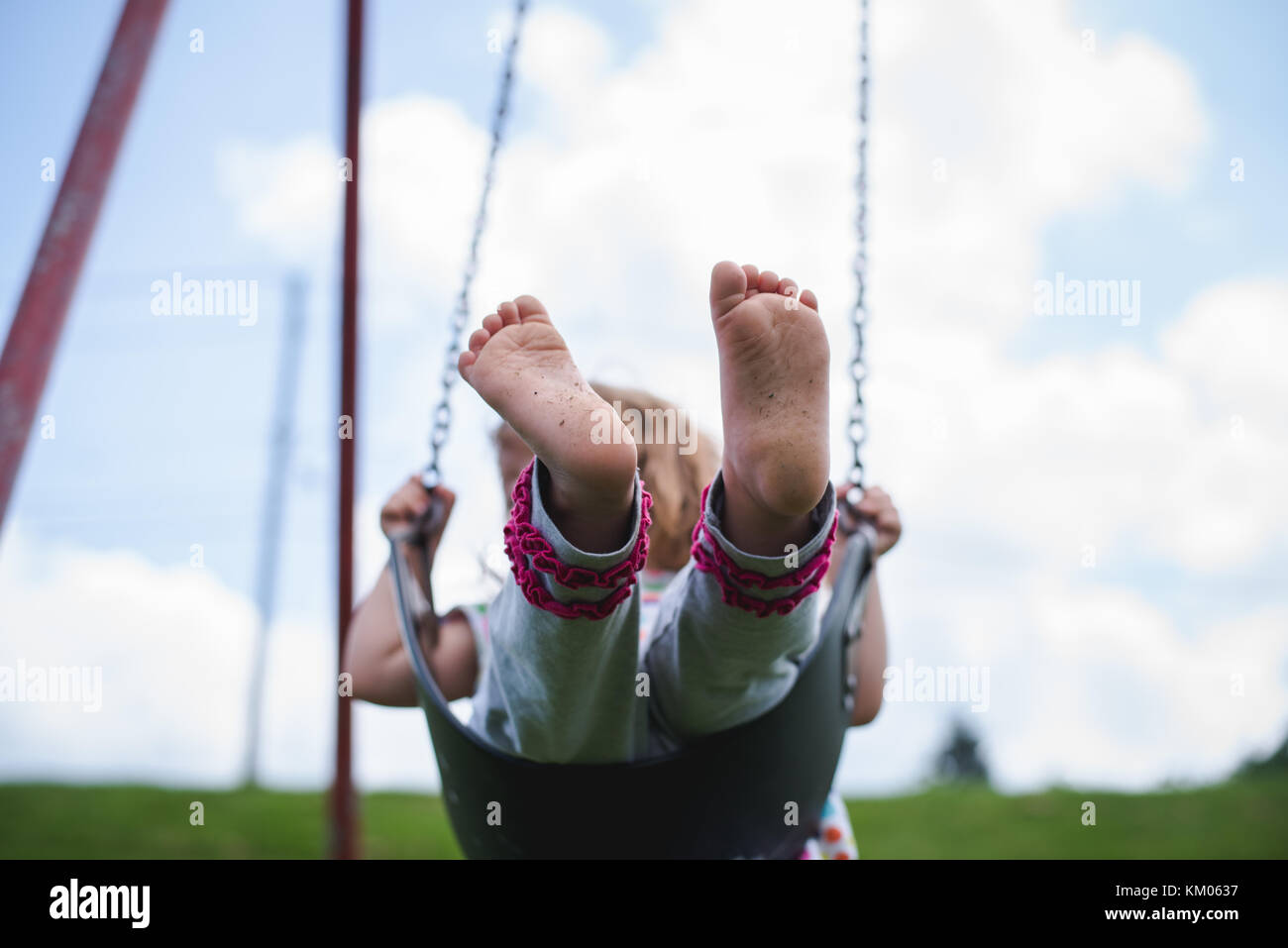 A young girl swings on a swing at a playground in bare feet Stock Photo -  Alamy