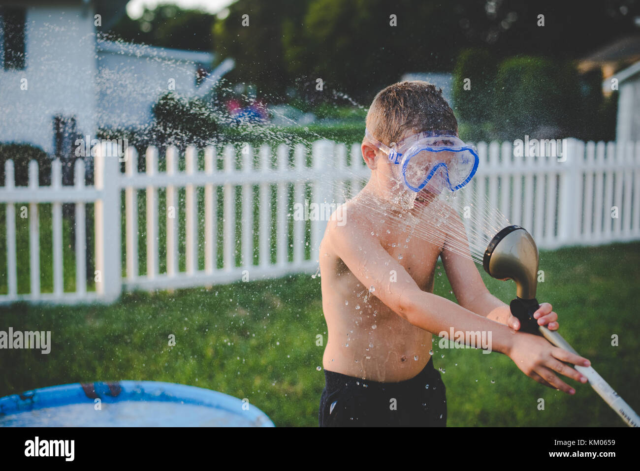 A 10year old boy sprays himself in the face with water from a