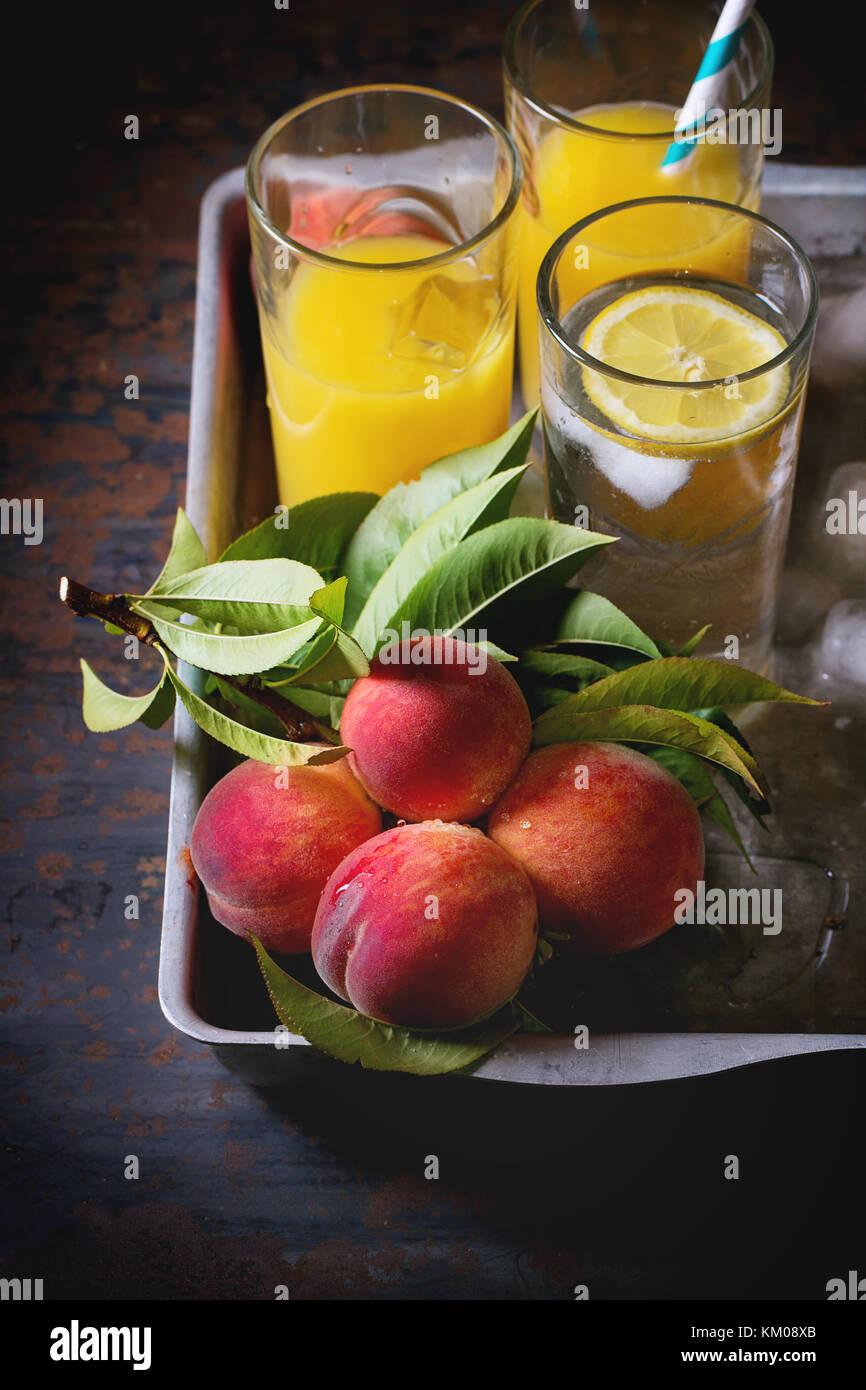 Peaches on branch with leaves and glasses with peach juice and limonade  with ice cubes in aluminum tray over old metal table. Dark rustic style  Stock Photo - Alamy