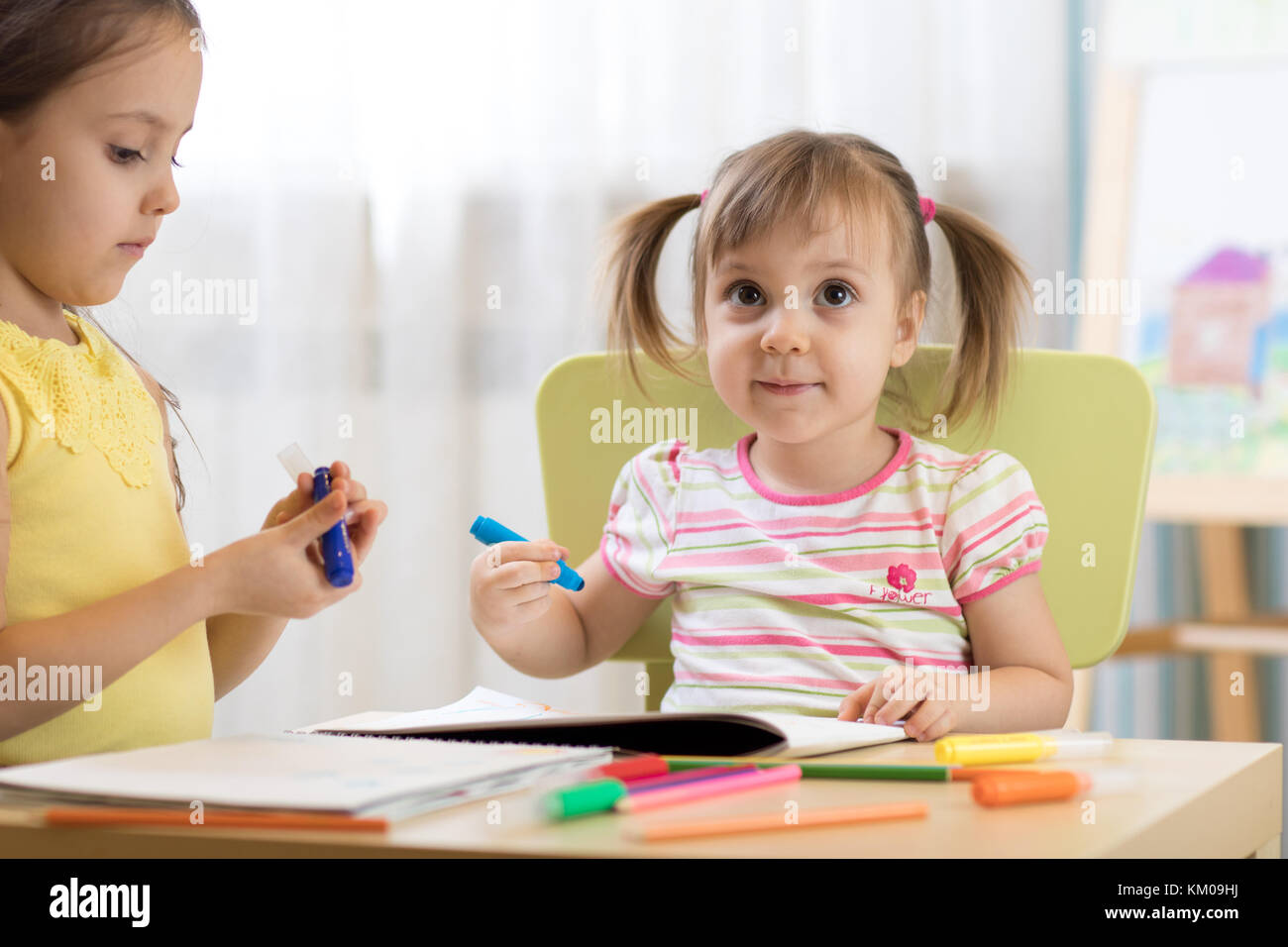 Kids drawing in kindergaten. Children paint in nursery. Preschooler with pen at home. Creative toddlers. Stock Photo