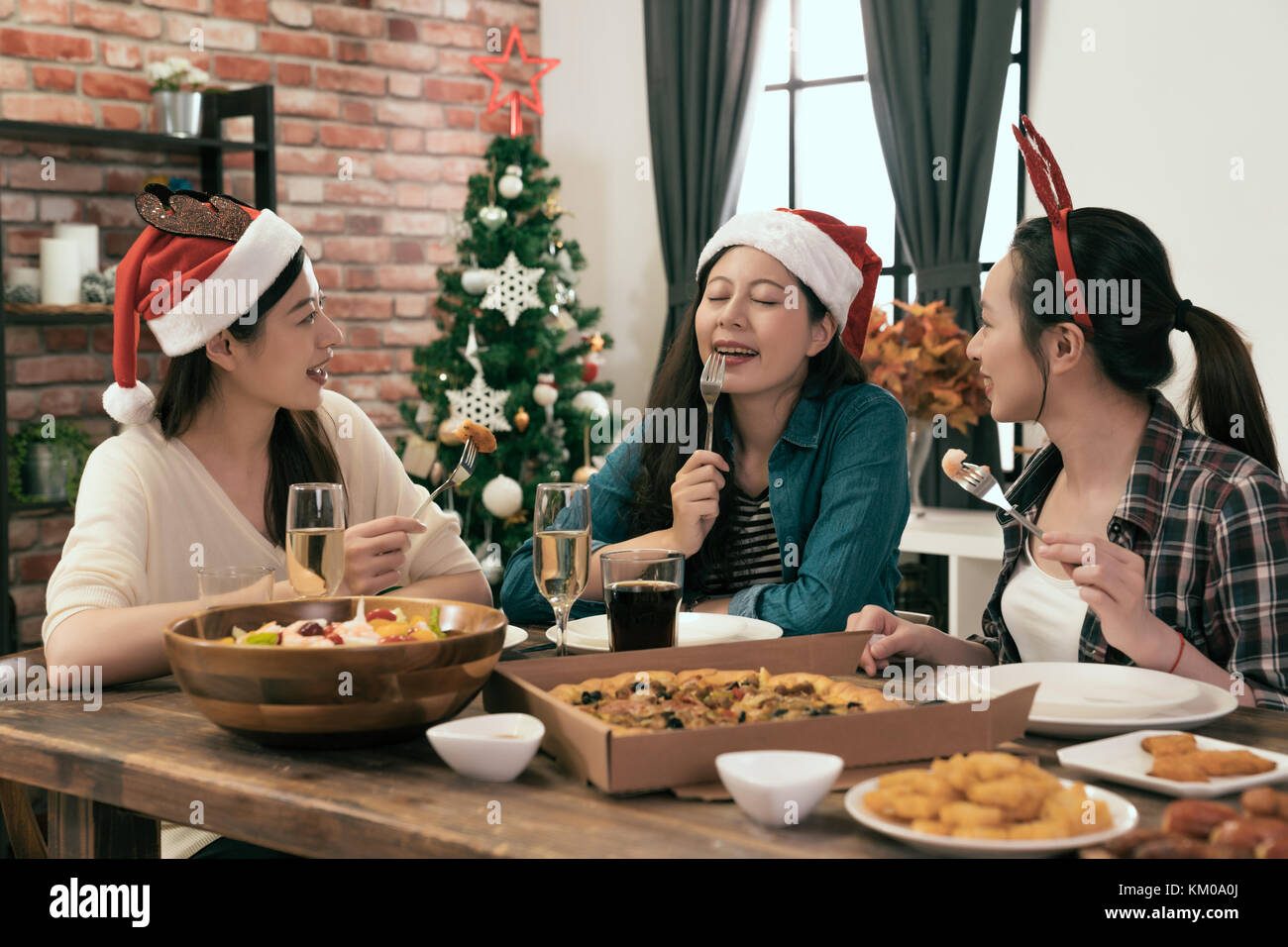 asia friends sitting around a wooden table and enjoying Christmas dinner together at home Stock Photo
