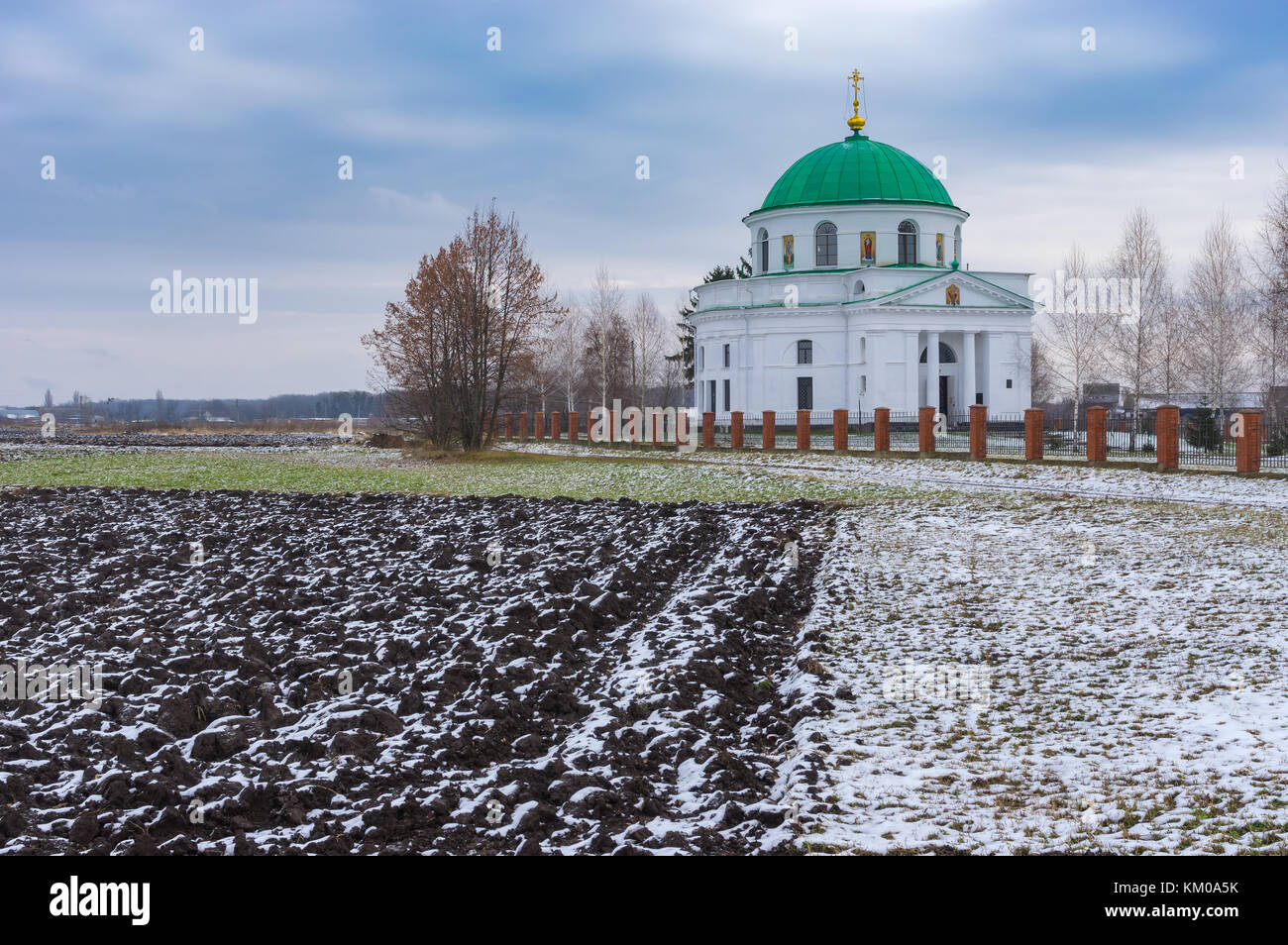 Landscape with agricultural fields near an ancient church of St. Nicholas (1797) in the urban settlement Dikanka, Ukraine. Stock Photo