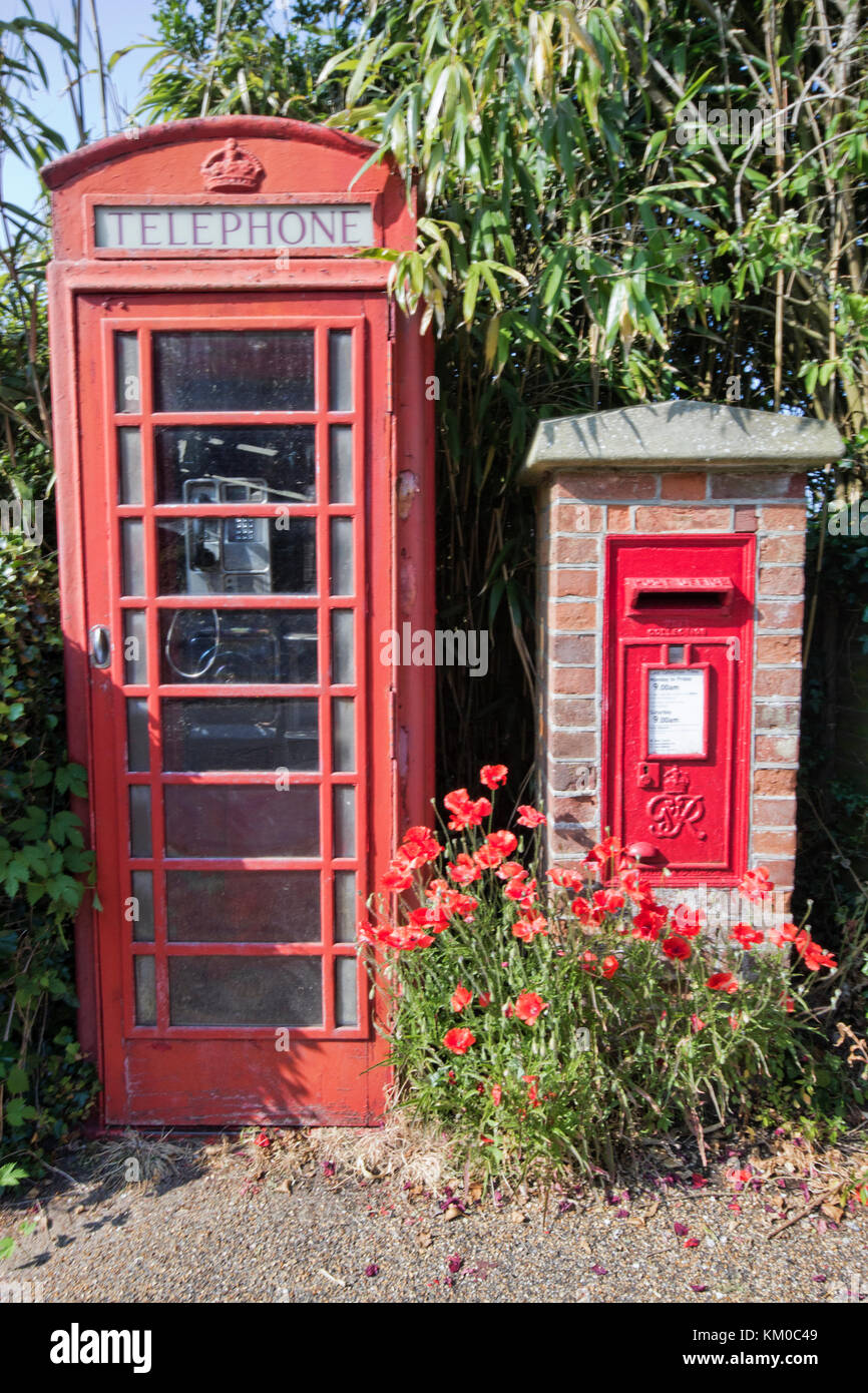 old style telephone box beside a red post box set into a brick wall