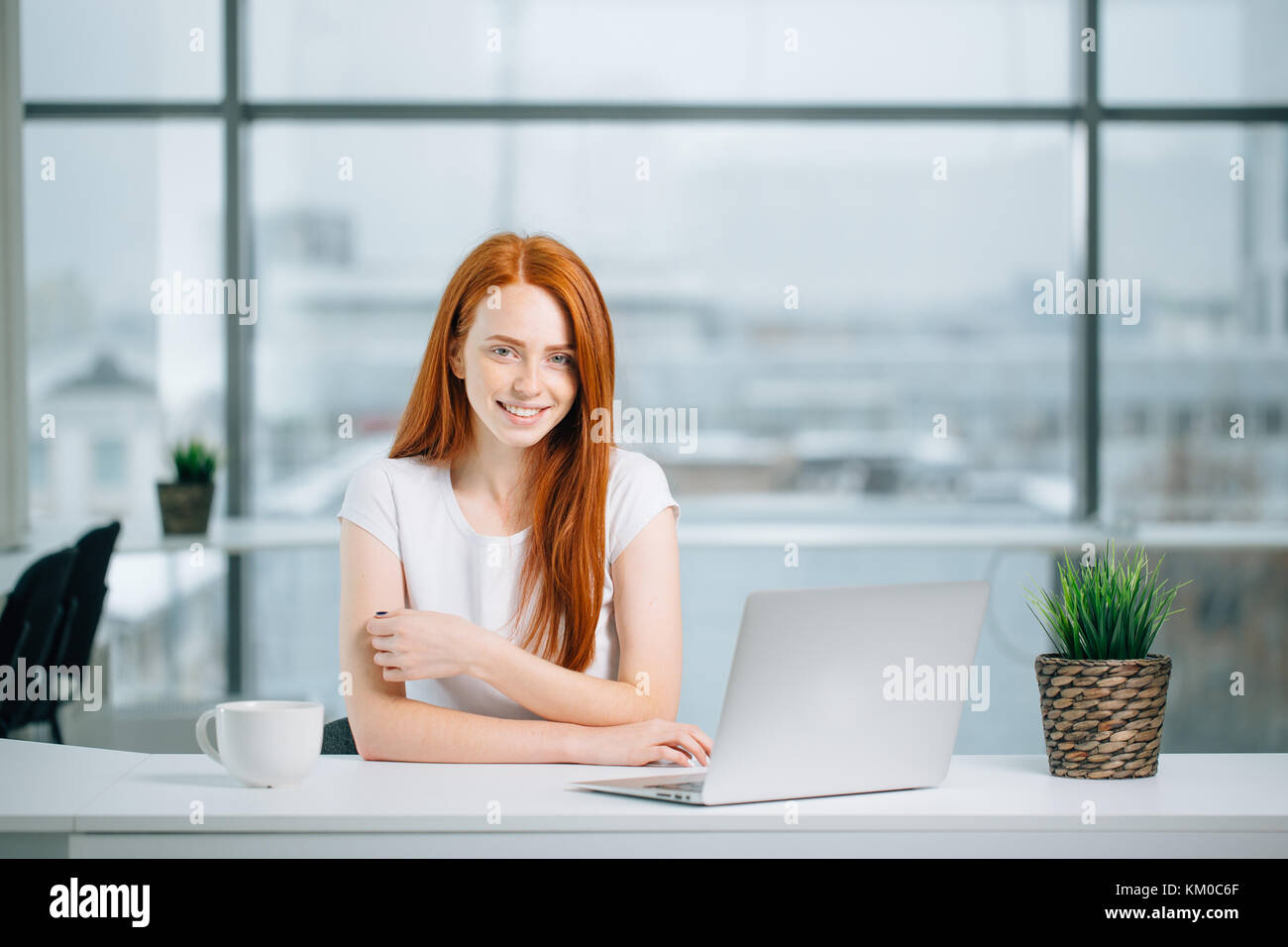 beautiful redhead girl works at laptop and looking at camera Stock ...