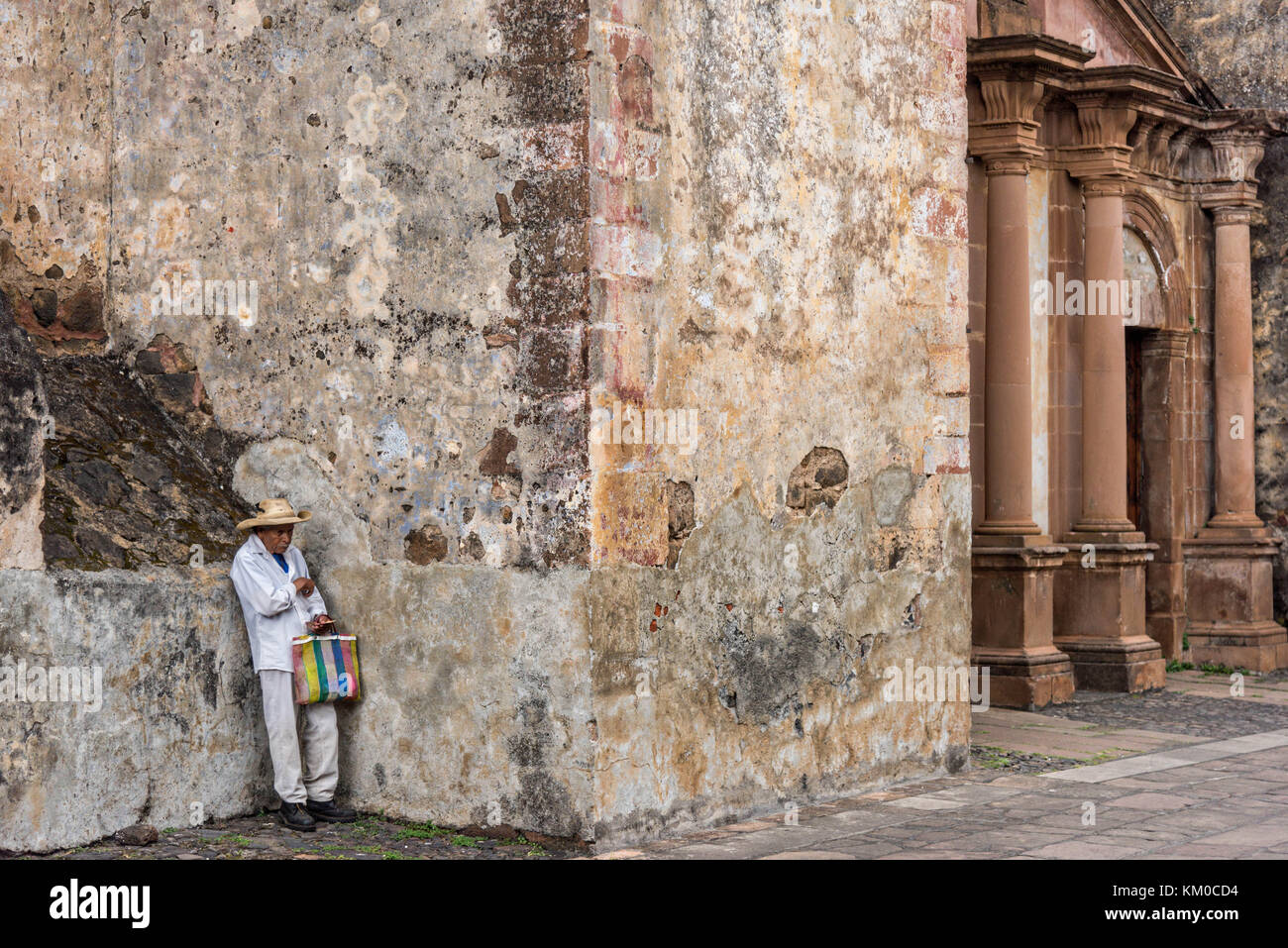 A Mexican farmer rests against a wall at the Templo del Sagrario in Patzcuaro, Michoacan, Mexico. Stock Photo