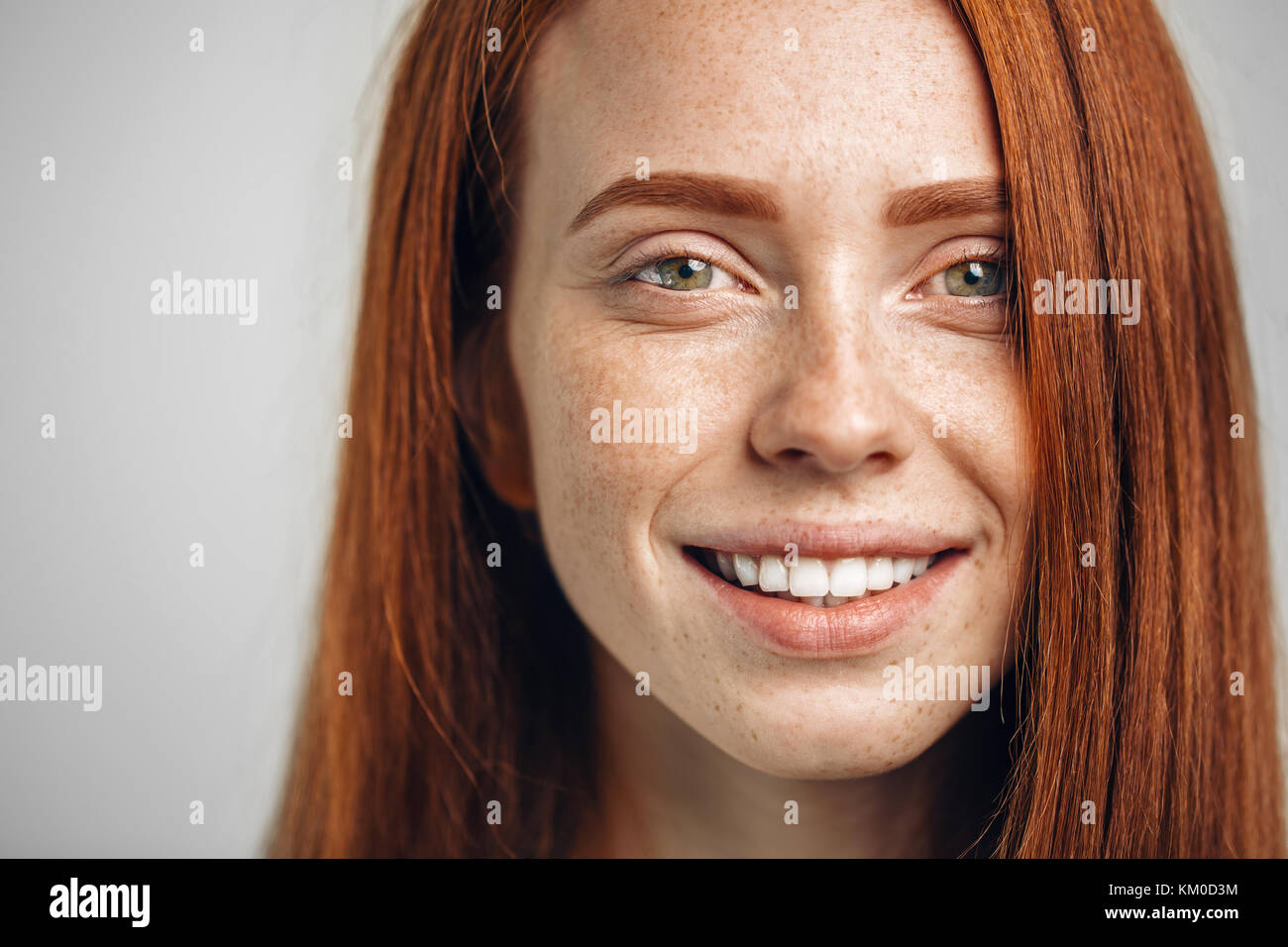 Headshot Portrait of happy ginger girl with freckles smiling looking at
