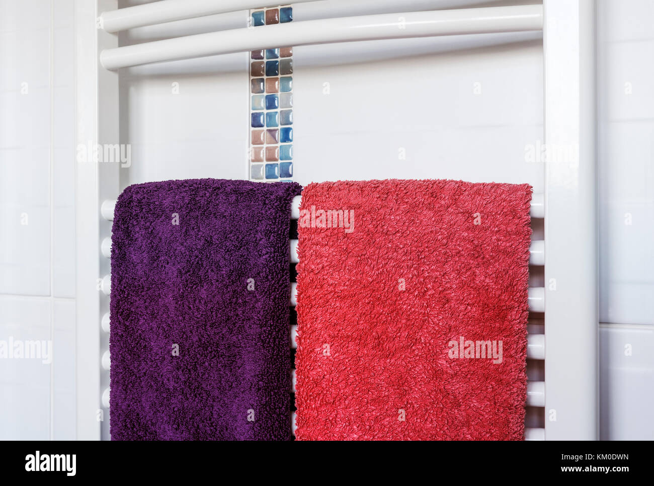 Heated white towel rail with towels. Stock Photo