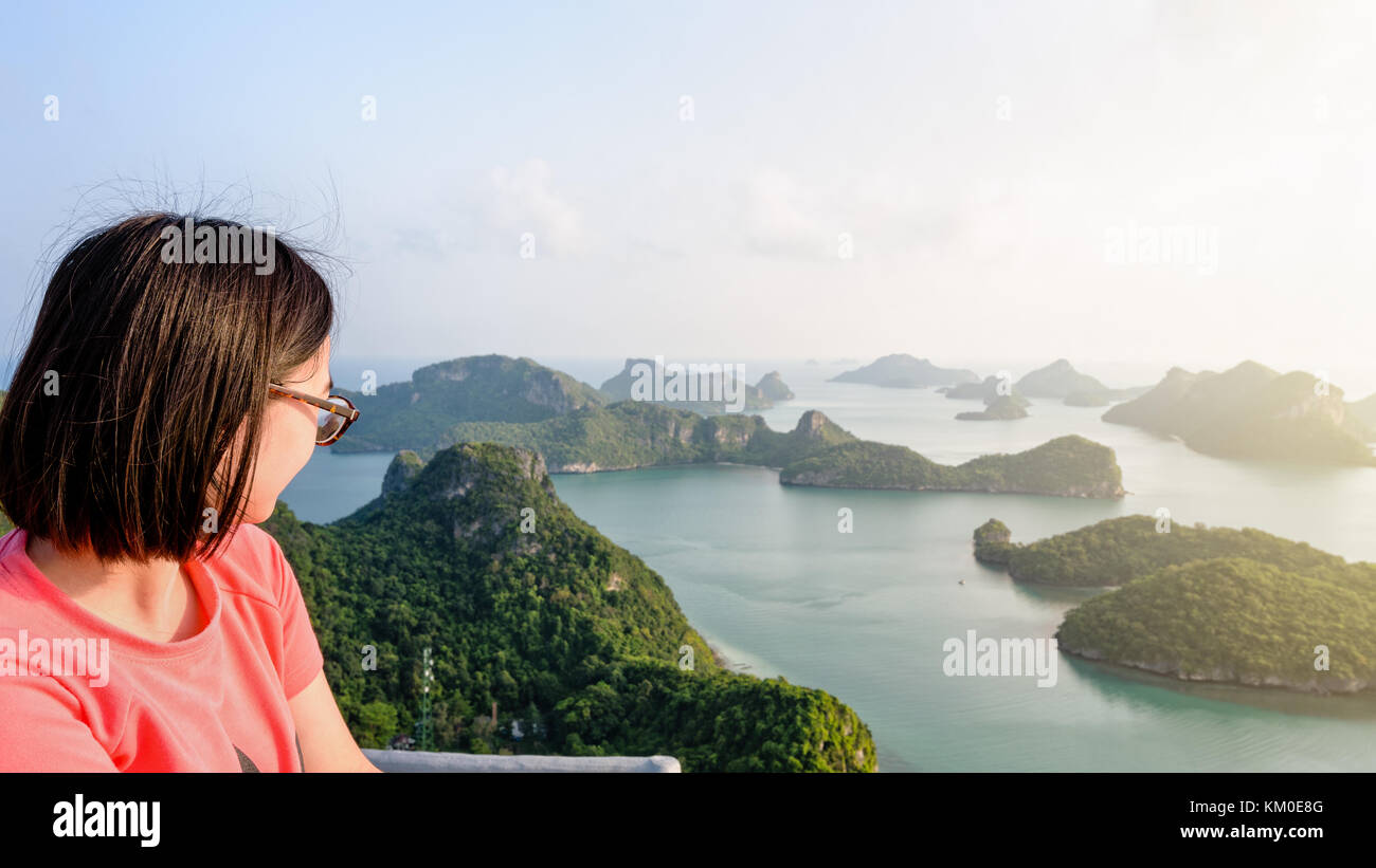 Woman tourist on peak view point of Ko Wua Ta Lap island looking beautiful nature landscape during sunrise over the sea in Mu Ko Ang Thong National Pa Stock Photo