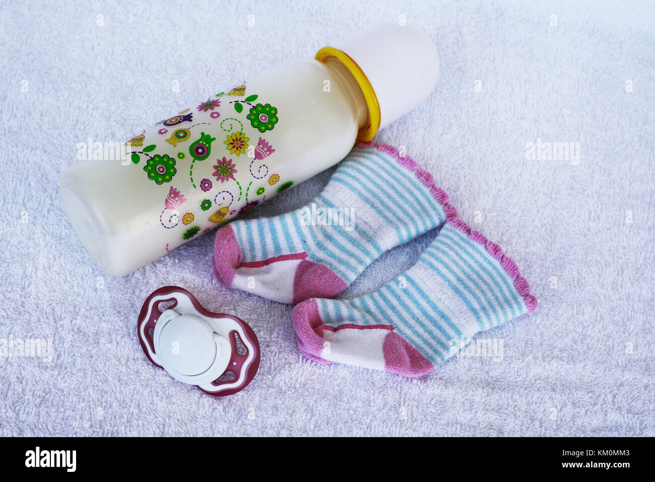 Set for newborn girl with baby milk, toy, pacifier, anti scratch hand guard mittens and socks on white background. Stock Photo
