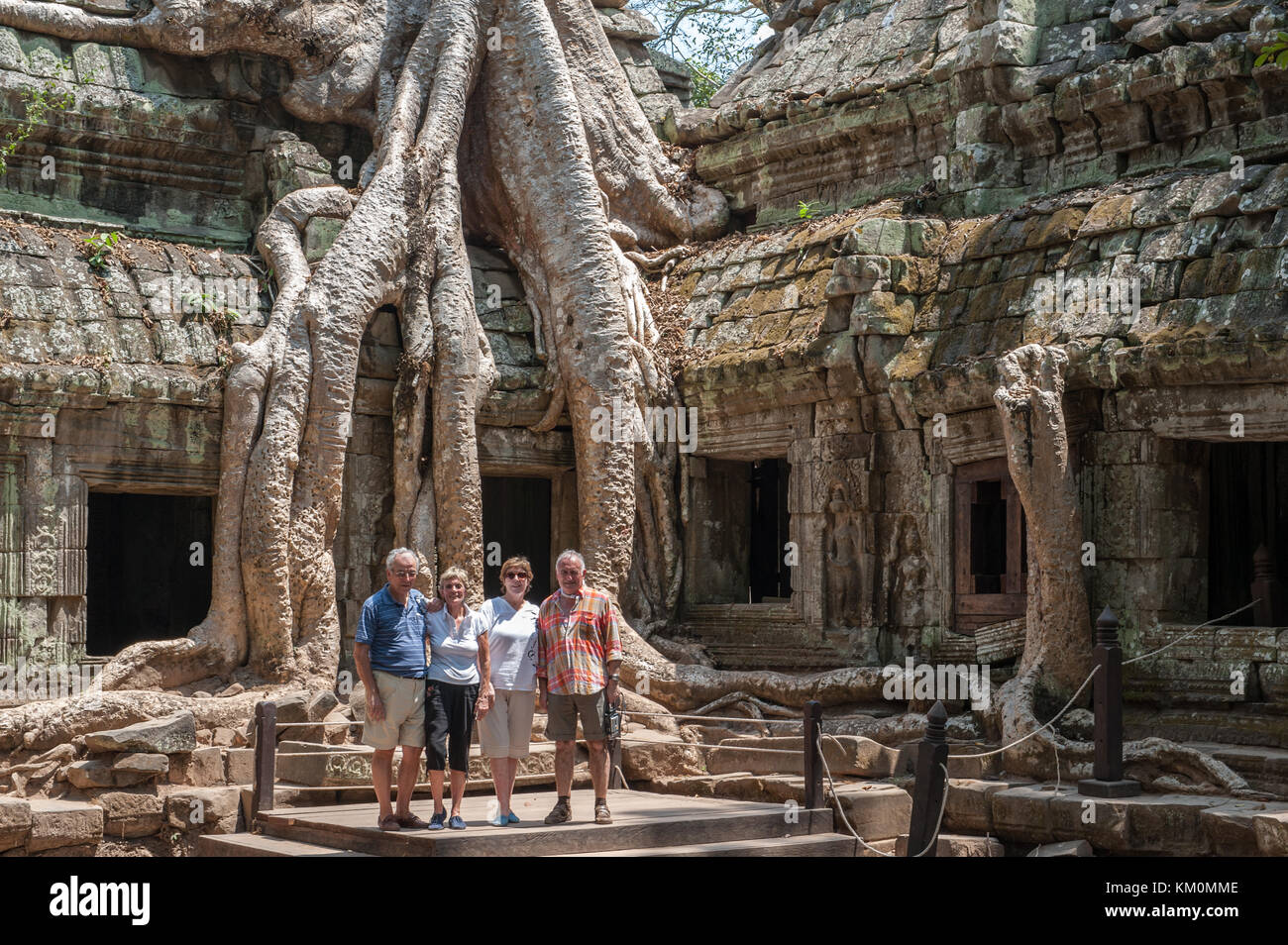 Tourists posing at Ta Prohm in Siem Reap. Built in 12-13th century Ta Prohm temple was later the location for the movie Tomb Raider. Stock Photo