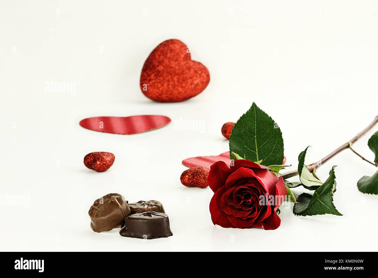 Beautiful long stem red rose with chocolate candy. Shallow depth of field. Stock Photo