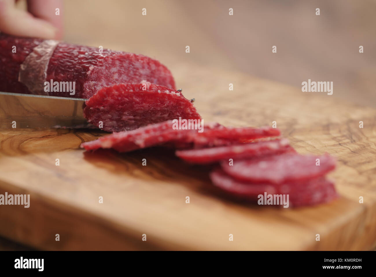 https://c8.alamy.com/comp/KM0RDH/closeup-female-slicing-thin-salami-sausage-wide-photo-KM0RDH.jpg