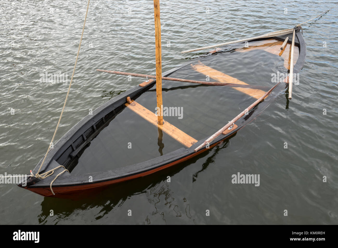 Wooden sailboat on the sea, water inside. Boat under water Stock Photo