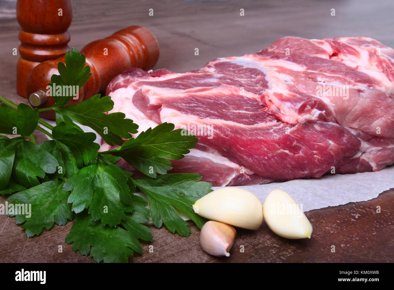 Raw pork neck chop meat with parsley herb leaves, grinder for spices