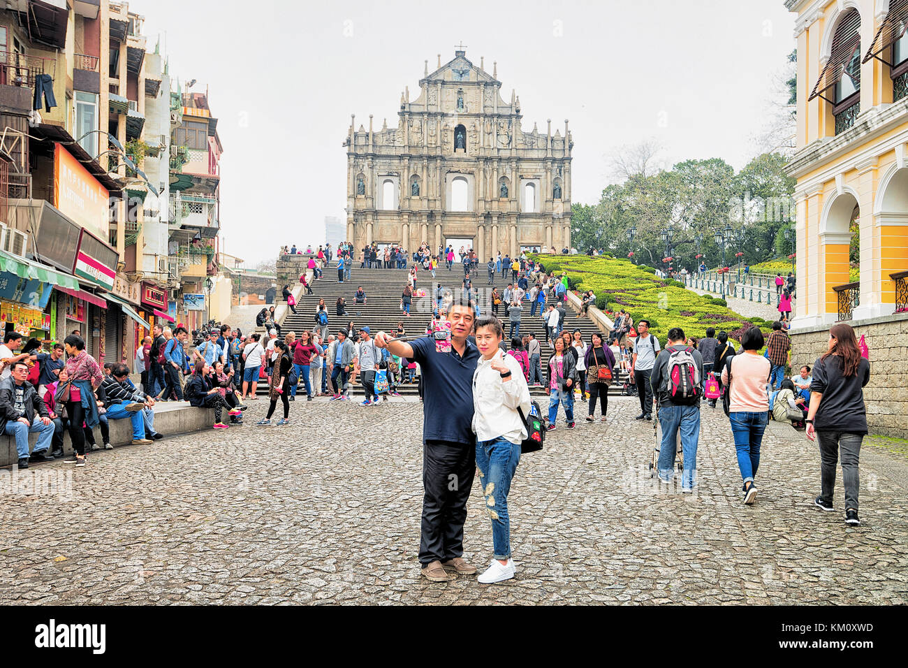 Macao, China - March 8, 2016: Couple making selfie photos at Ruins of Saint Paul Church in Historical old city center in Macao, China. People on the b Stock Photo