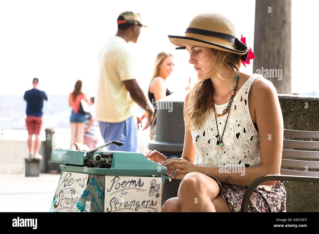 Seattle, Washington, USA - September 4th, 2017: A young woman is writing poems for customers with a typewriter in the street at the waterfront of Sea Stock Photo