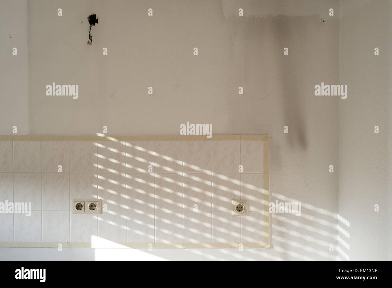 Wall in a kitchen with wallpaper, tiles and sockets befor renovation ...