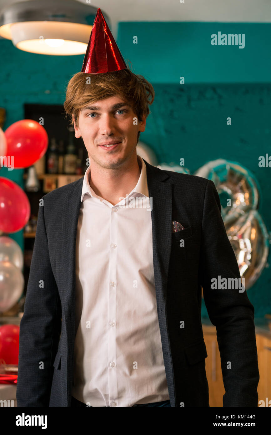 Young adult man celebrating new year eve or eighteenth birthday in cozy apartment indoor. Stock Photo