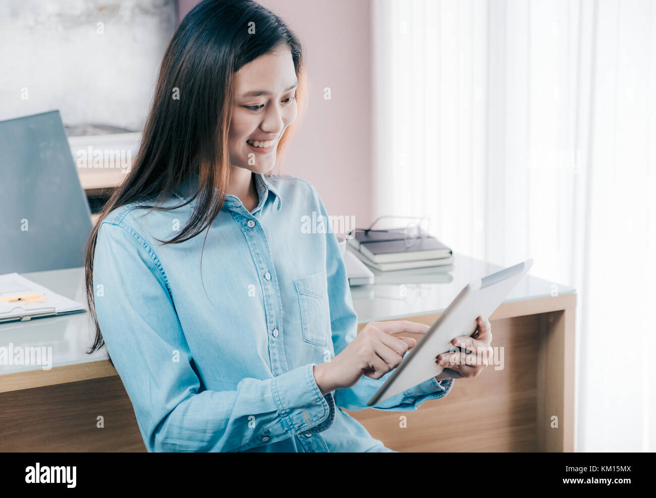 Asian businesswoman use tablet to online conference meeting with smiling face,Happy office life concept,working woman at modern home office. Stock Photo