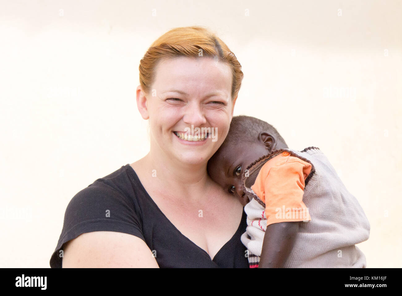 A happy white woman - a missionary - holding an African boy. Stock Photo