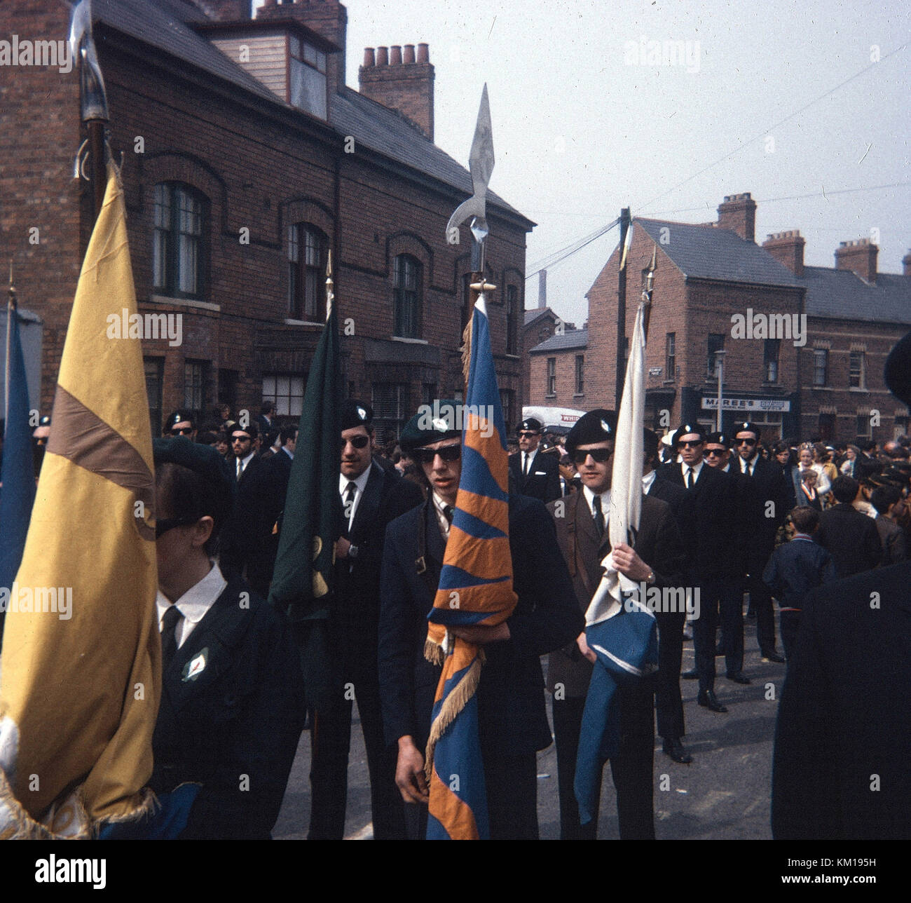 IRA colour party and republican easter parade on beechmount avenue west Belfast 1970. This easter parade signalled the split between the official and provisional IRA. The official IRA used stick on easter lillies (so became known as the stickies) and the provisional IRA wore pin on badges. This is the pin on parade Stock Photo