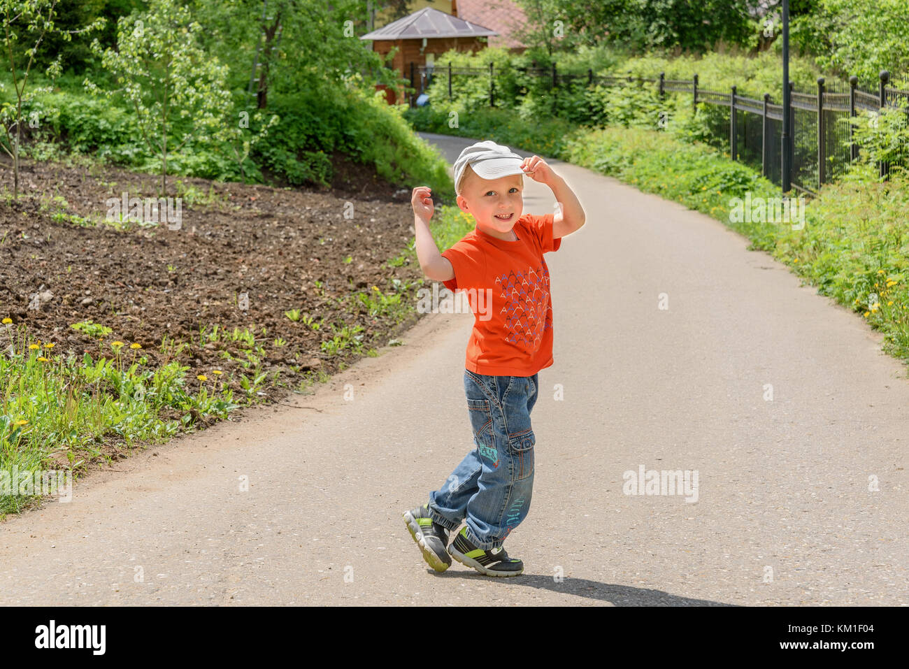 A little boy in an orange shirt and jeans walking along a path in a park  Stock Photo - Alamy