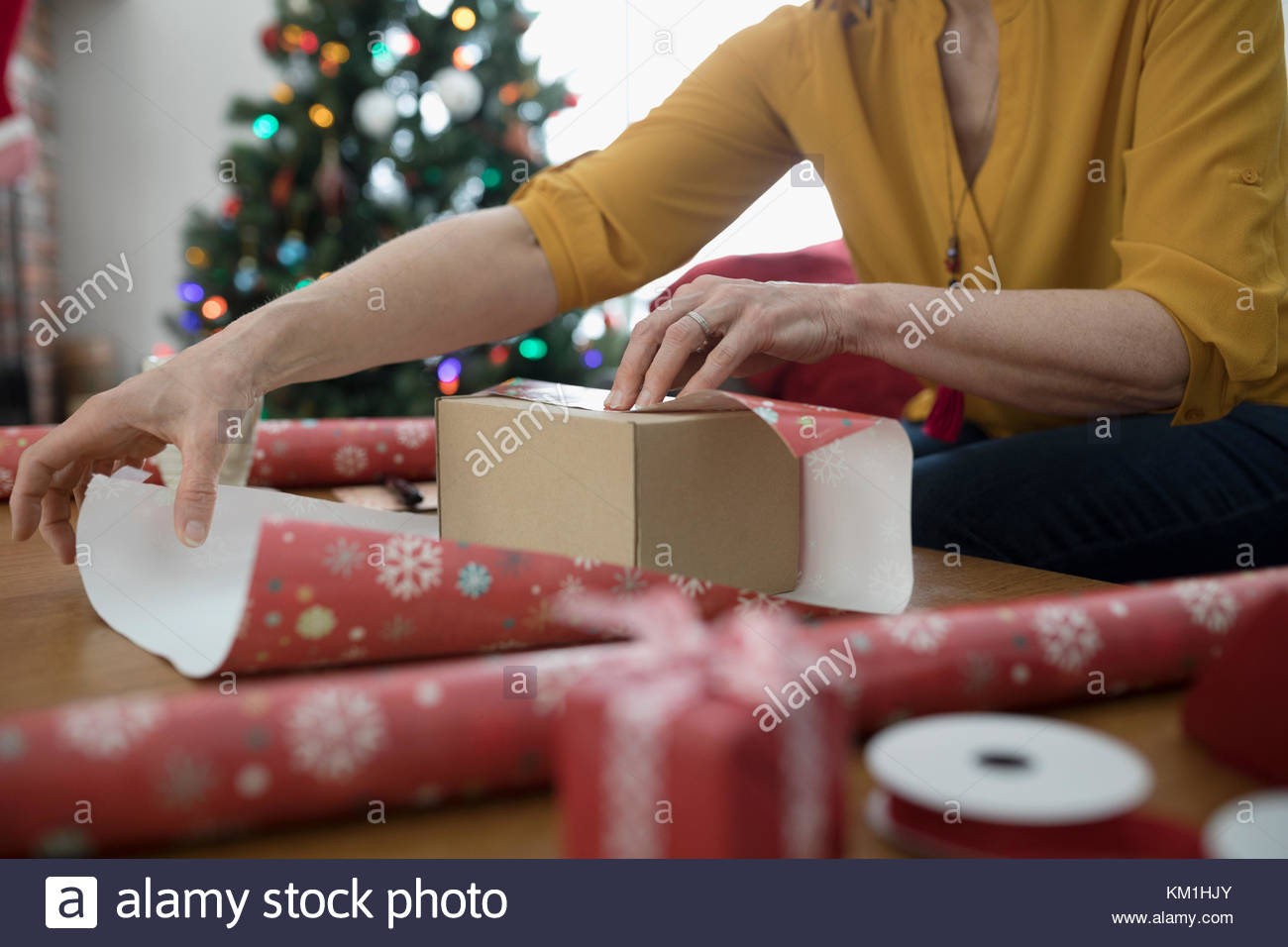 Woman wrapping Christmas gift with wrapping paper Stock Photo