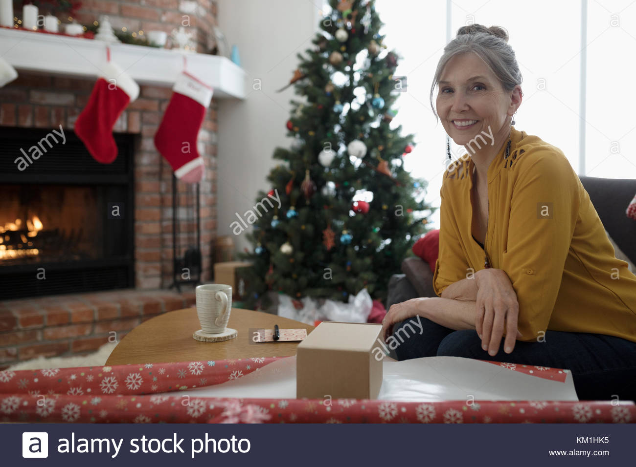 Portrait smiling mature woman wrapping Christmas gifts in living room