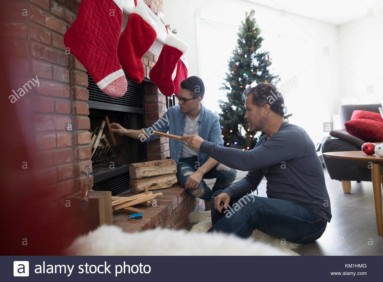 Father Teaching Son How To Build A Fire In Fireplace In Christmas