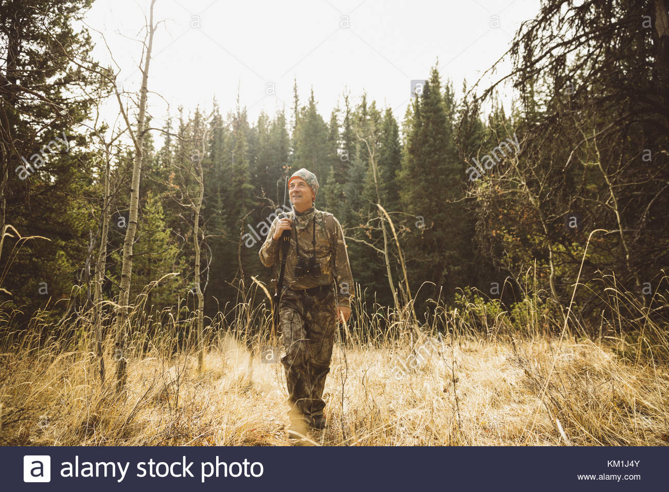 Senior hunter in camouflage hunting, walking in remote field Stock