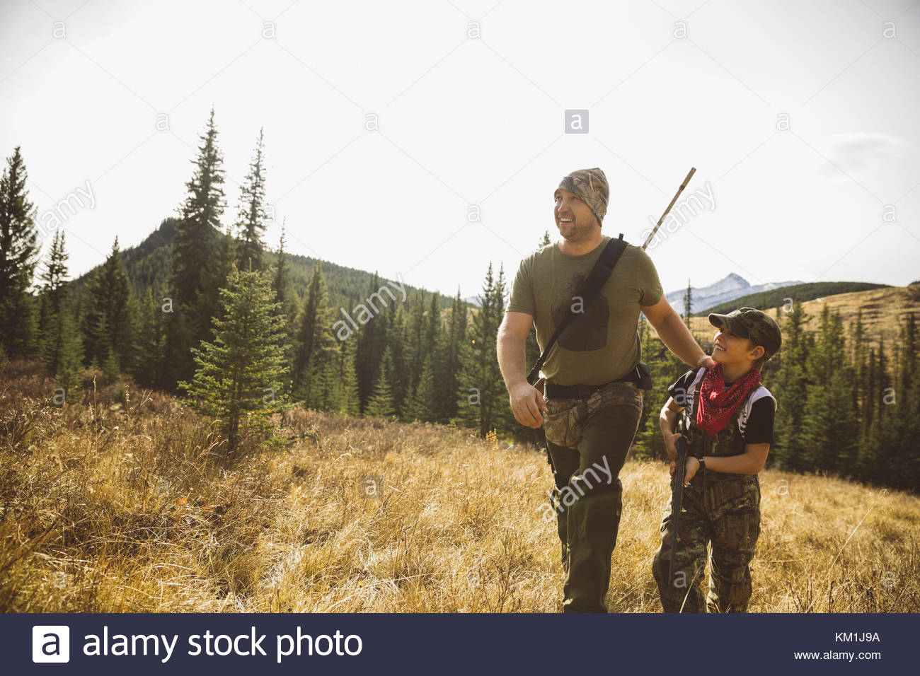 Father and son hunters with rifles bonding, hunting and walking in