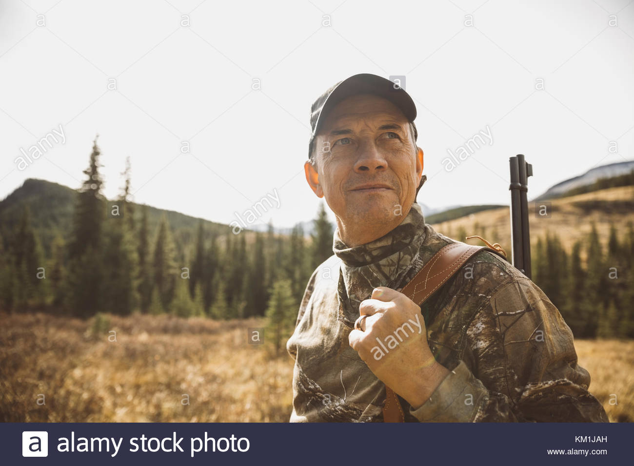 Serious male senior hunter carrying hunting rifle in remote field Stock