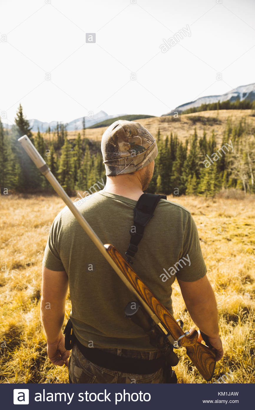 Male hunter with hunting rifle in remote field Stock Photo Alamy