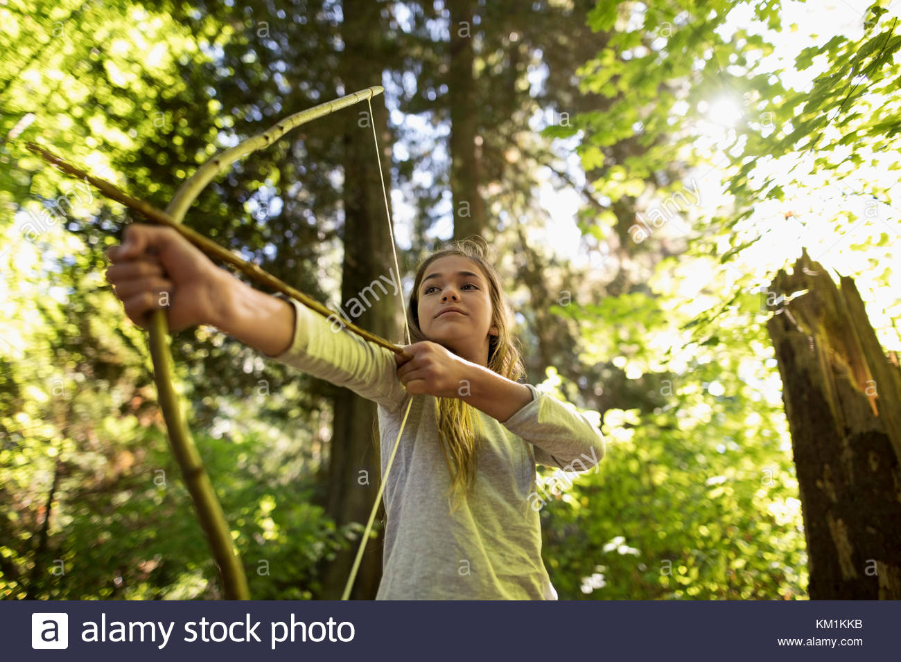 Confident girl aiming bow and arrow in woods Stock Photo