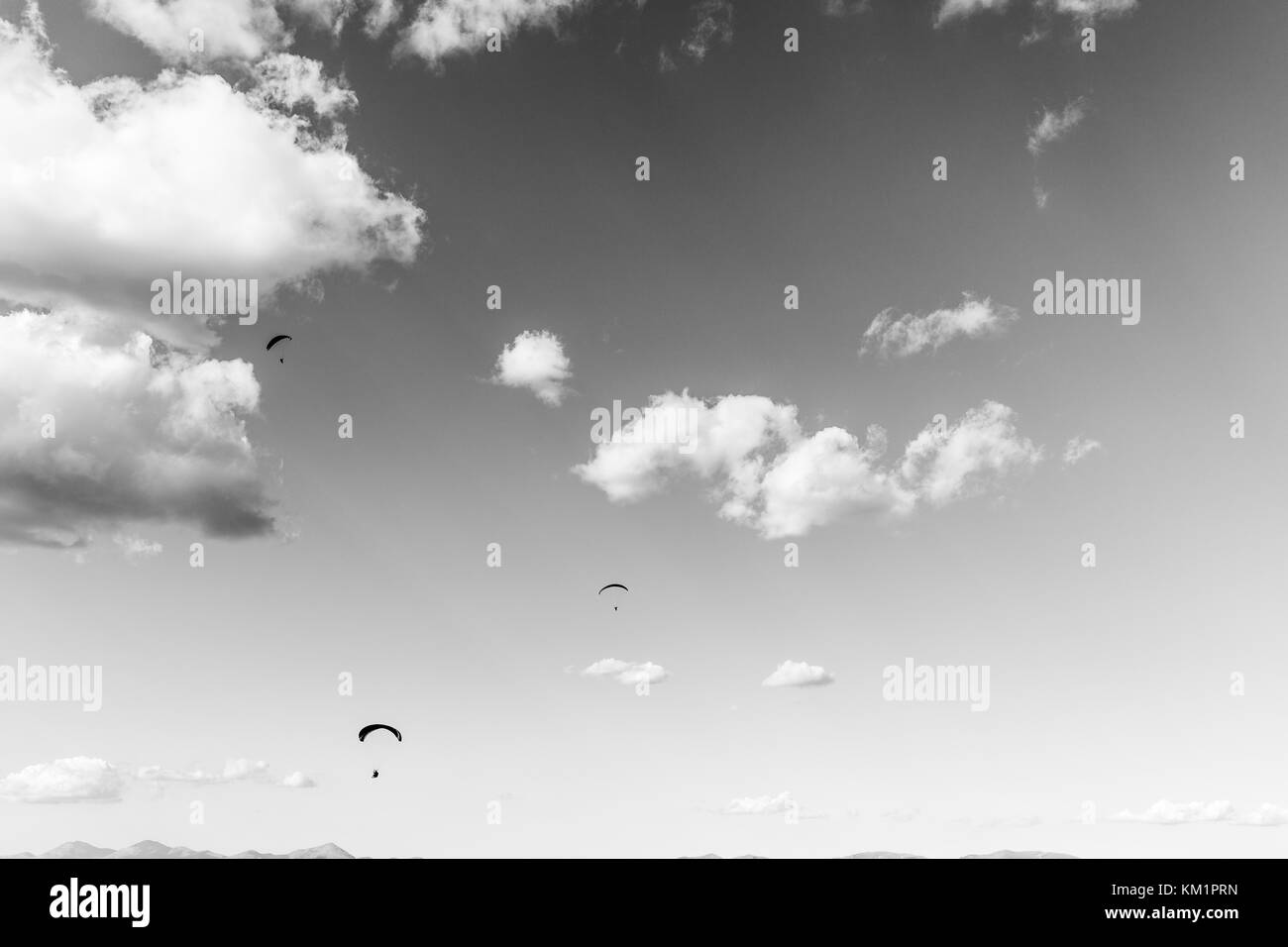 Three para gliders flying against a deep sky, with big white clouds Stock Photo