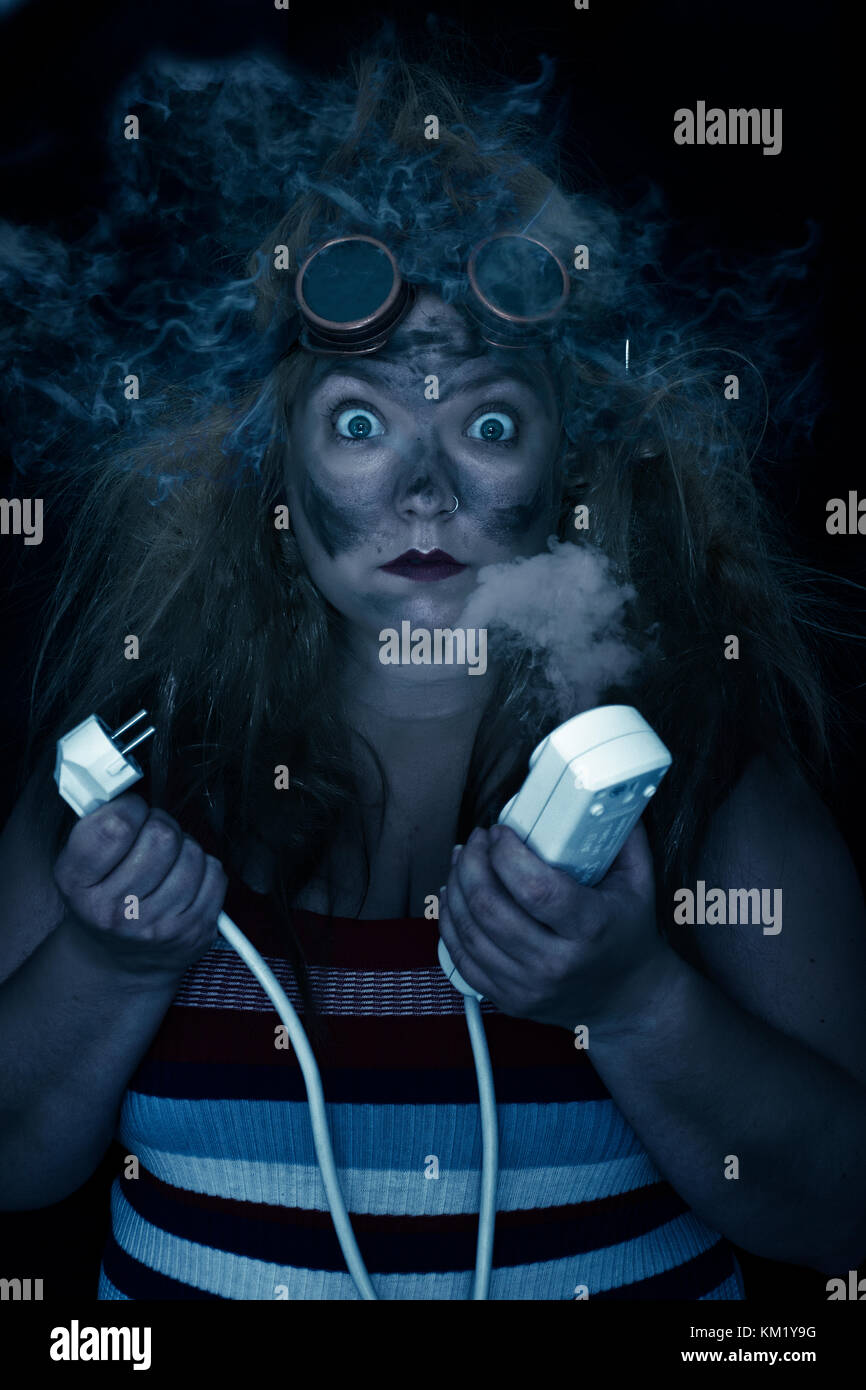 Woman with a cable in her hands with smoke in her hair. Mujer con cables en las manos después de hacer corto circuito Stock Photo