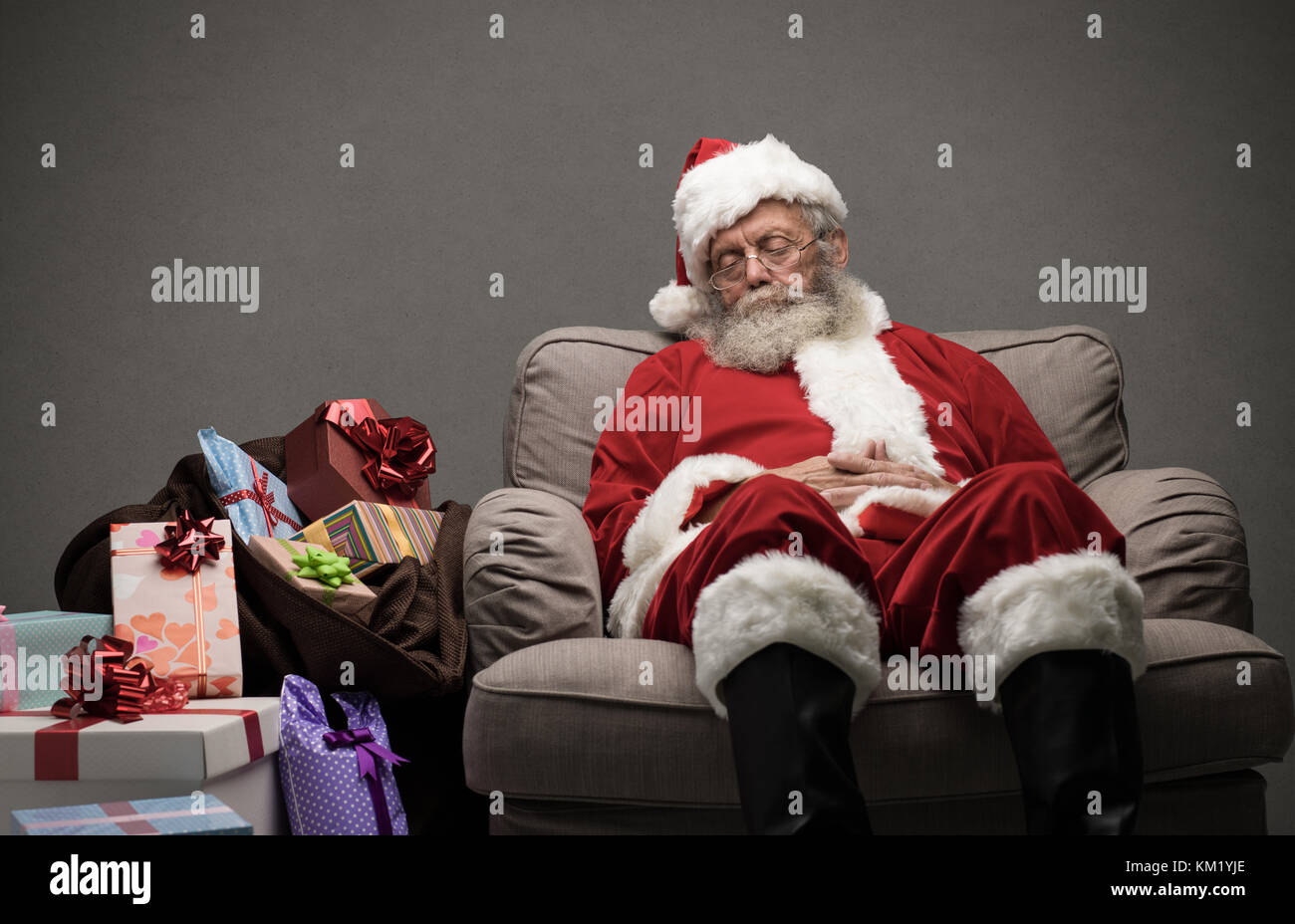 Sleepy Santa Claus taking a nap and relaxing on the armchair on Christmas Eve Stock Photo