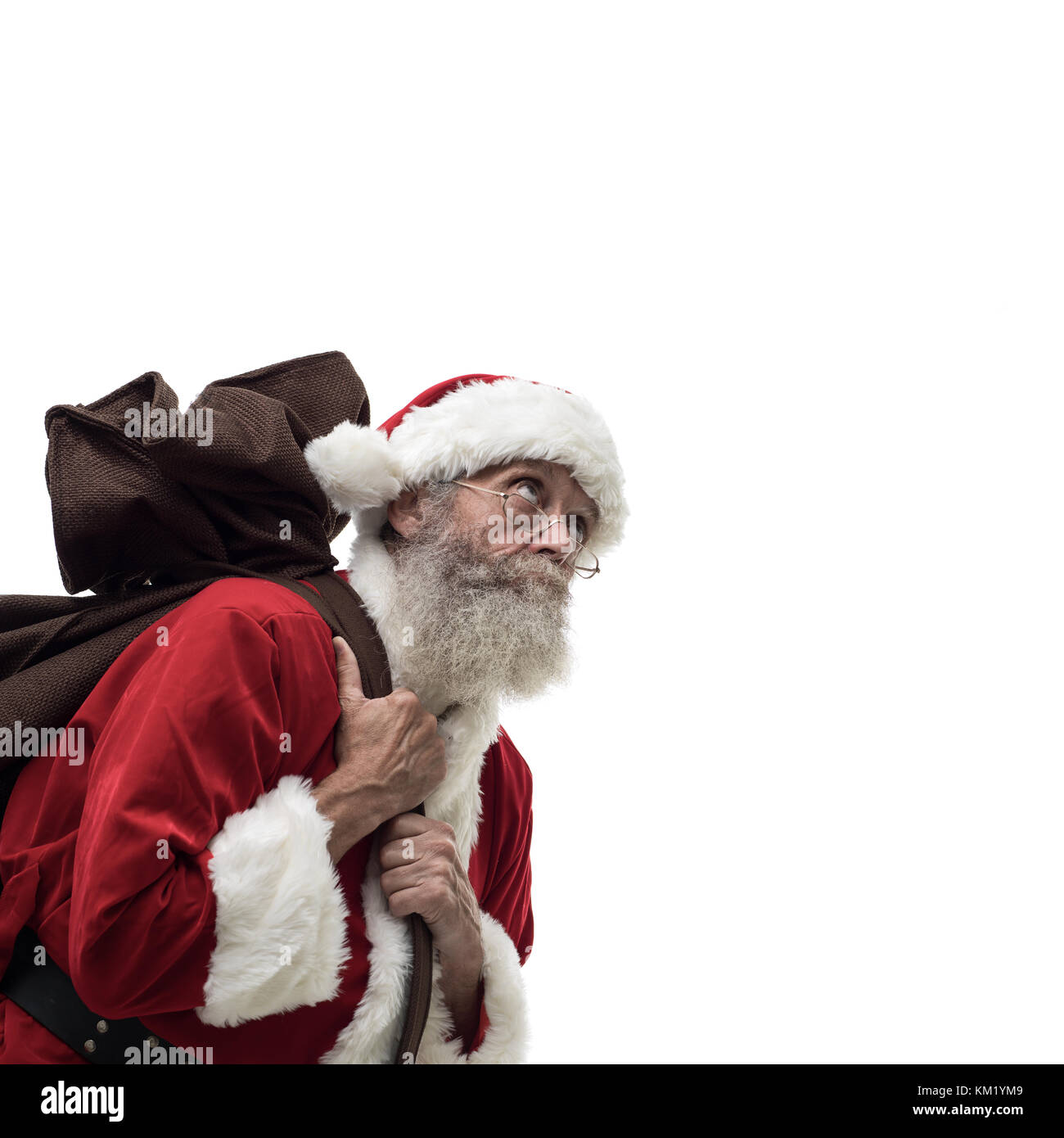 Happy Santa Claus carrying an heavy sack with Christmas gifts, white background Stock Photo