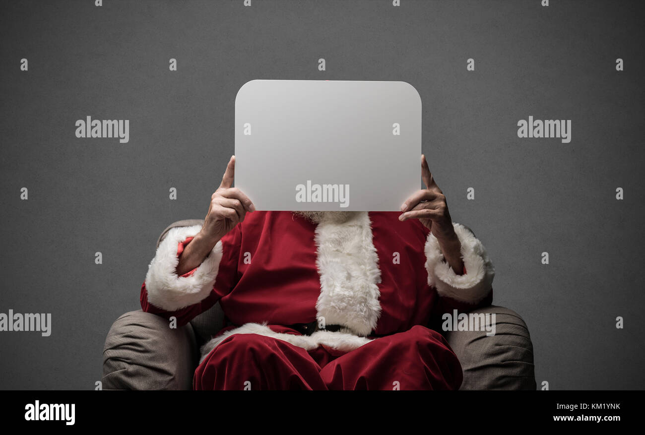 Santa Claus sitting on an armchair and holding a blank sign, Christmas ...