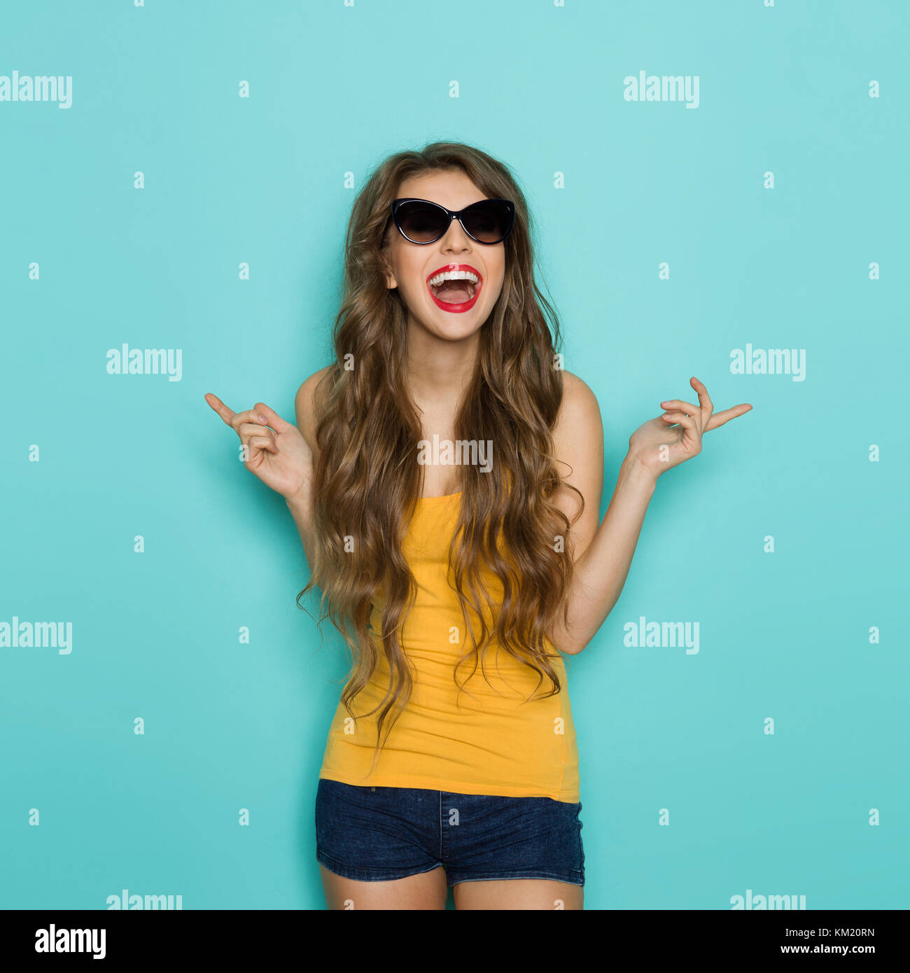 Shouting young woman in sunglasses, jeans shorts and orange shirt