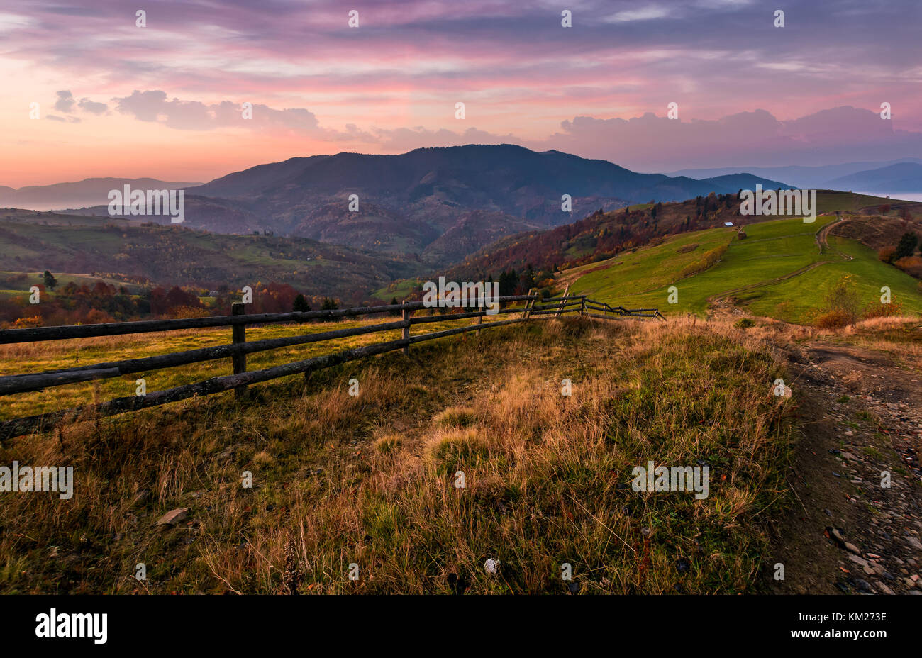 wooden fence on a grassy rural hillside at autumn dawn. gorgeous ...