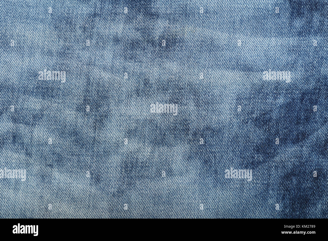 Dark indigo blue cotton jeans denim texture background with light washed distressed faded area, close up Stock Photo