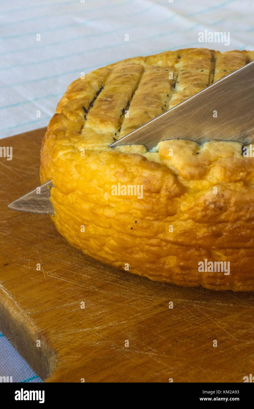 cut head of traditional Adygei cheese handmade with knife on wooden