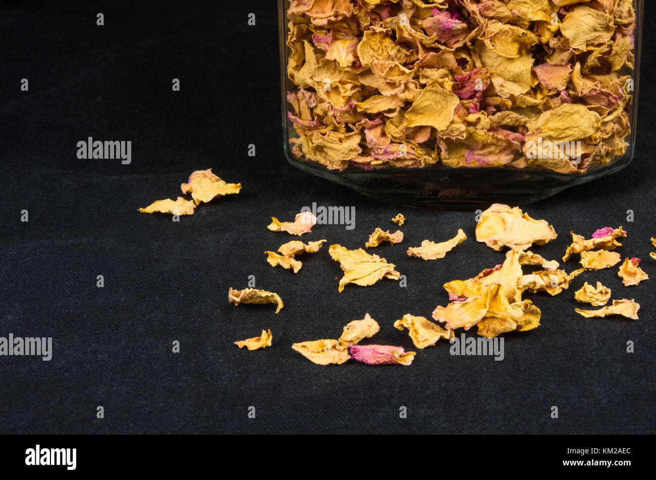 dried rose petals in a glass jar with lid on a black background Stock