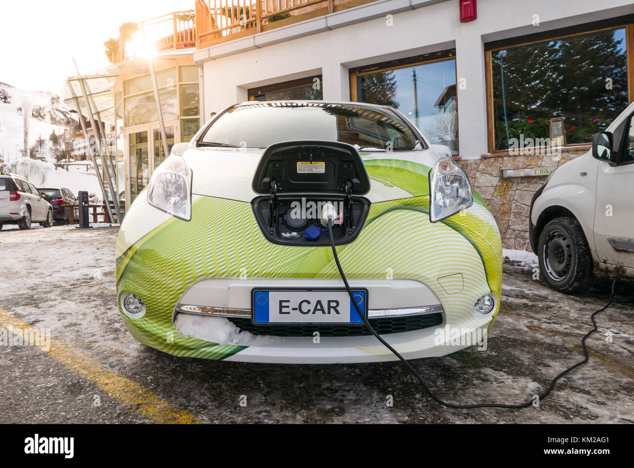 Front side of electric car cobered with snow charging on the street in ...