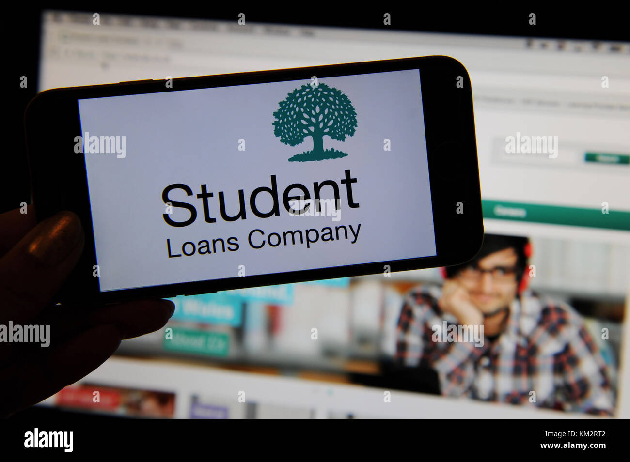 The Student Loans Company logo on a phone with the website on a computer screen Stock Photo