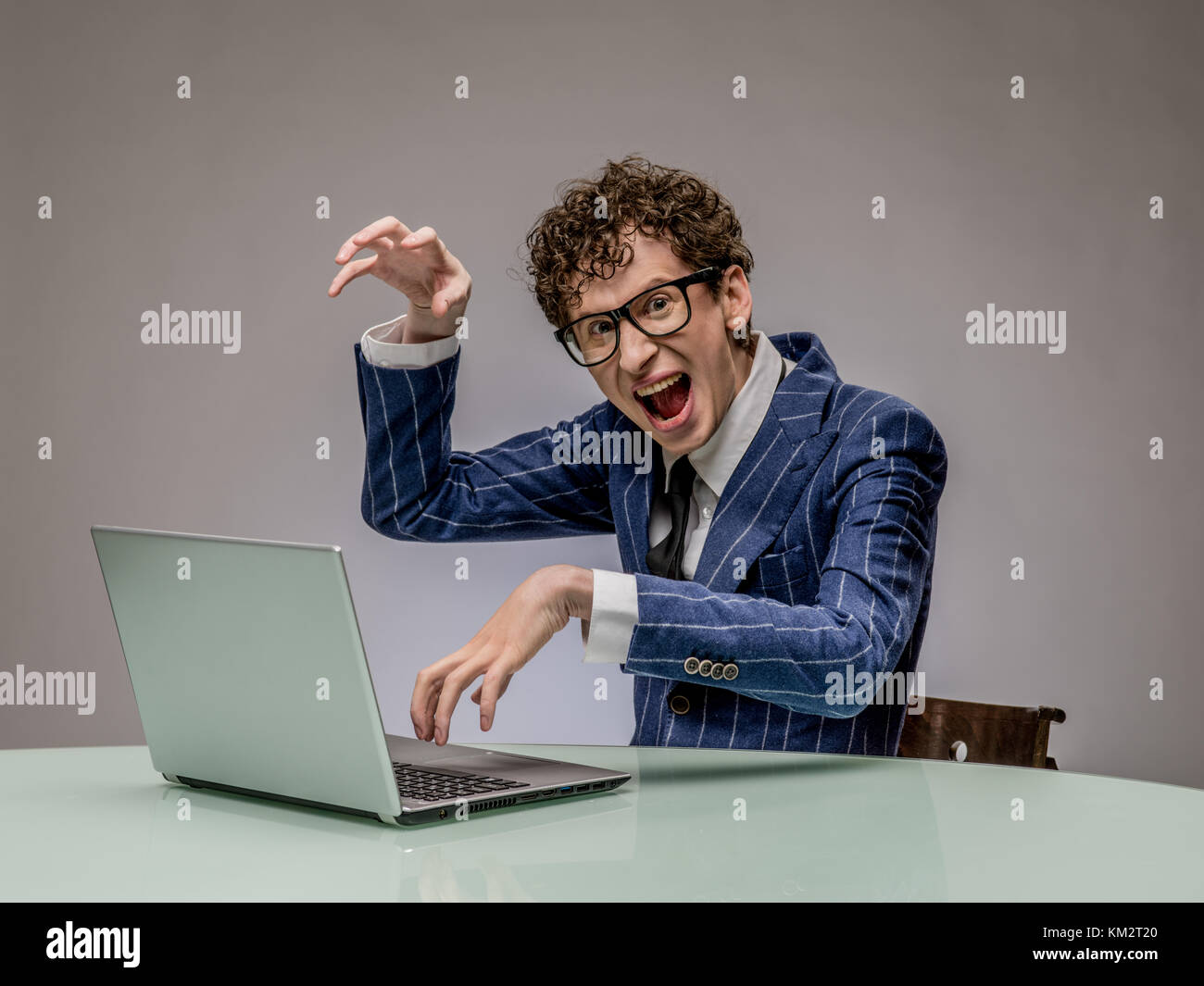 Funny business man geek using laptop with evil genius facial expression Stock Photo