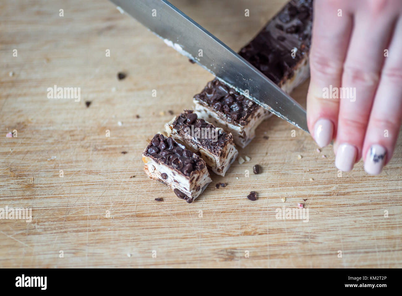 Female Hands Cutting Chocolate and Nut Nougat with Knife on Wooden ...