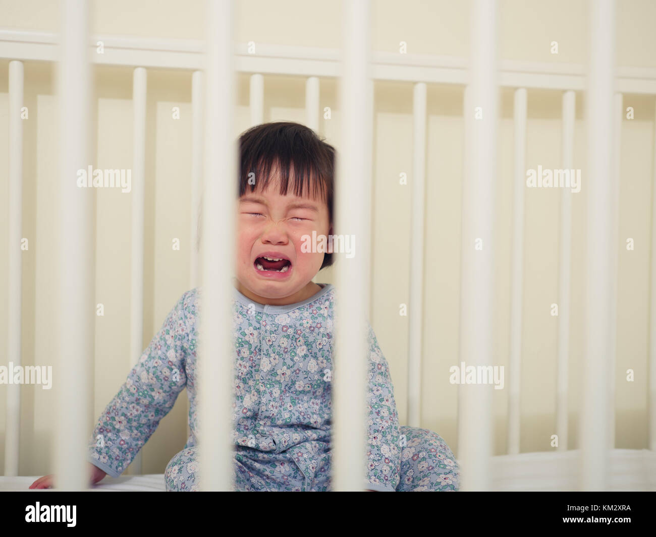 Crying Baby girl in cot bed Stock Photo Alamy