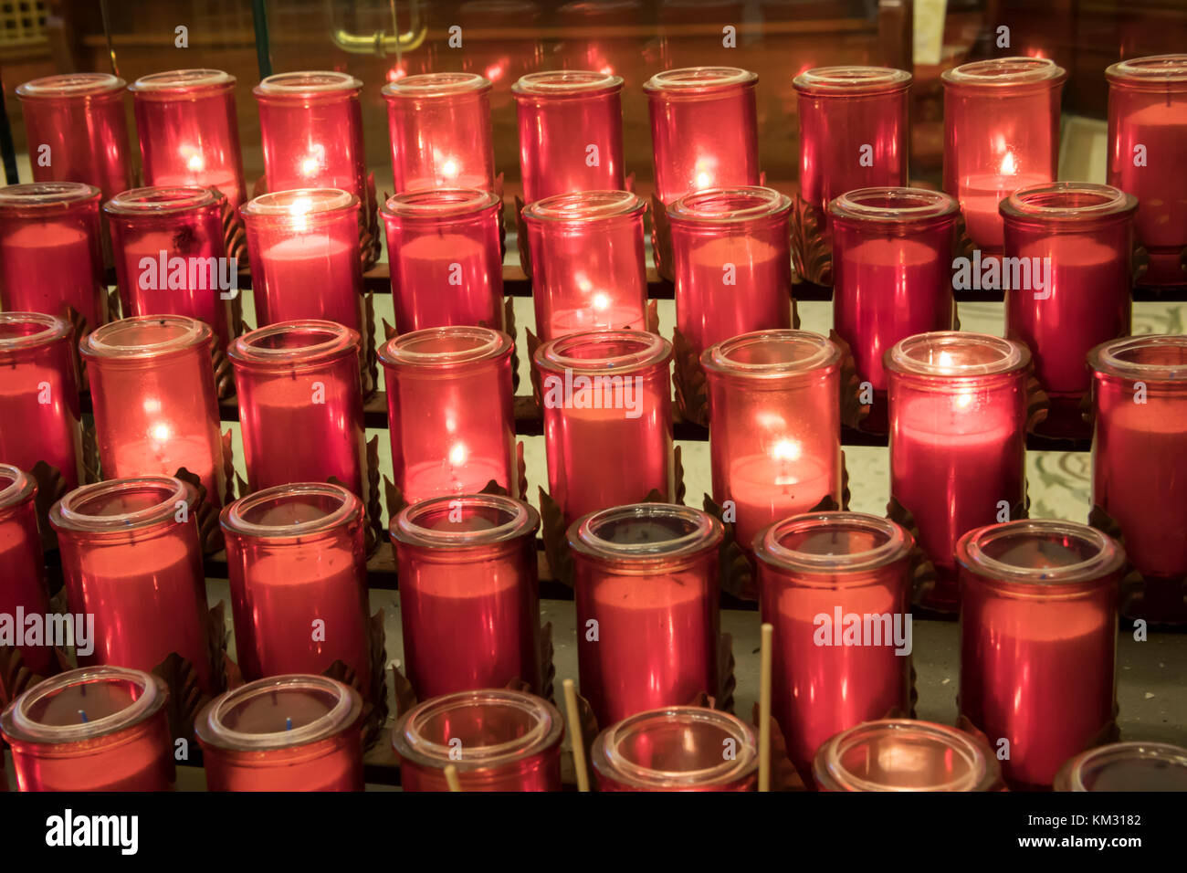 Red candles lit in prayer inside church Stock Photo Alamy